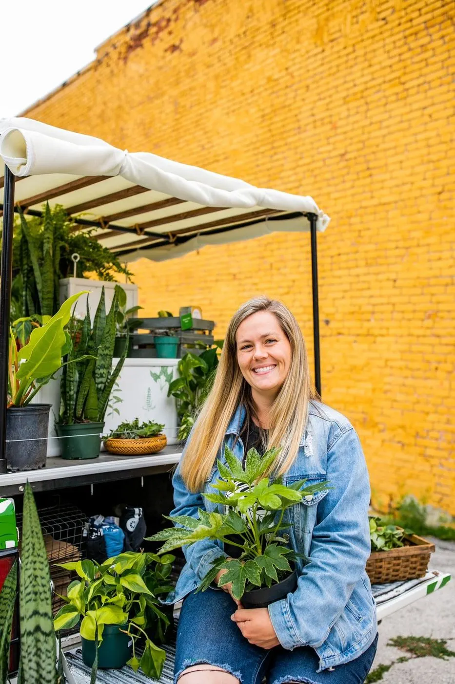 Tasha on the tailgate of Mobile Joe, holding a plant